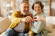 © Home-stock - Retired couple buy house. Senior spouses become homeowners receiving key from new home in realtor office after closing deal