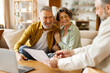 © Home-stock - Realtor or broker showing documents and house plan to excited senior couple, agent or consultant help mature spouses with bank loan or mortgage at briefing