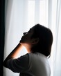 © Derek Brumby - Silhouette of a Thoughtful Woman in Natural Light by Sheer Curtains