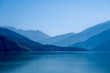 © ProMicroStockRAW - Multilayered blue mountains are shrouded in mist, with blue light cascading over them and the lake waters. This picturesque scene at Tehri Lake captures the enchanting interplay of light and nature.