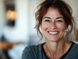 © Veronika - Woman smiling warmly while sitting indoors in a cozy environment with soft lighting during the day, showcasing a relaxed and happy moment