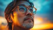 © anatolii - Man gazing thoughtfully at a colorful sunset with vibrant hues illuminating the sky during twilight in an outdoor setting