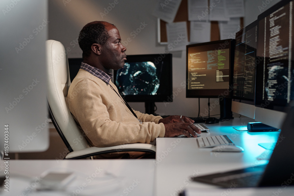 Side view of serious mature male programmer typing on computer keypad ...