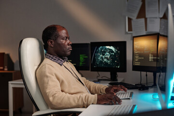 Poster - Serious African American IT manager or programmer decoding data on desktop computer screen while sitting by workplace