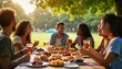 © miss irine - Group of young multicultural friends enjoying outdoor lunch in community park. Friends smiling, chatting eating food, drinks. Casual attire, happy atmosphere. Sunny day with nature background. Fun,
