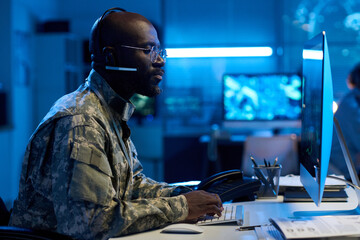 Aufkleber - Young serious military operator in uniform typing on keypad and looking at computer screen while sitting by workplace