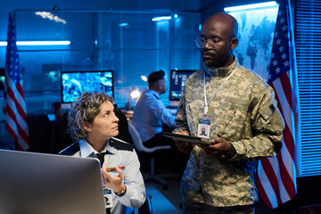 Aufkleber - Serious mature female officer in uniform pointing at computer screen and looking at young male colleague during discussion