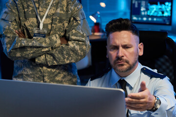 Aufkleber - Serious mature man in uniform looking at desktop computer screen with misunderstanding while sitting next to colleague