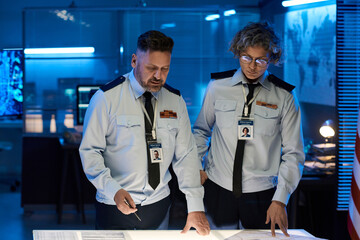 Aufkleber - Two mature male and female officers of military command center looking at paper documents on table and discussing them