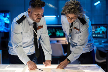 Aufkleber - Mature male and female military officers bending over table with paper documents while pointing at data during presentation
