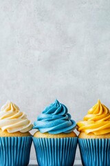 Wall Mural - Colorful cupcakes with blue and yellow frosting on a light background