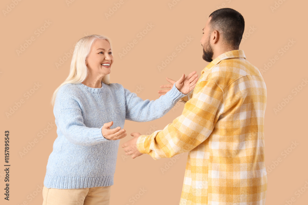 Young man with his mother opening arms for hug on beige background