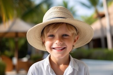 Wall Mural - Portrait of a cute little boy in a straw hat on the beach