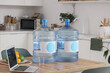 © Pixel-Shot - Bottles of clean water with laptop on table in kitchen