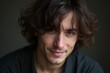 © I.J. Wheeler - Young Man with Curly Hair Smiling Against a Dark Background
