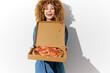 © VICHIZH - Happy young woman with curly hair holding a pizza box, celebrating delicious food in a bright atmosphere, perfect for food lovers and culinary trends
