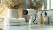 © zulie - White hair dryer on marble bathroom counter with folded towels and toiletries.