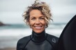 © Igor - Portrait of smiling senior woman in wetsuit with surfboard