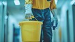 © fajar - A person in a blue uniform is holding a yellow bucket