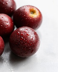 Sticker - Close-up of fresh, red, juicy plums with water droplets on a light gray surface.