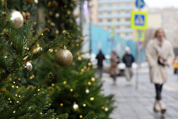 Wall Mural - New Year celebration in city, golden toy balls on a street on blurred background of walking people