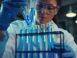 © Сергей Кошкаров - Scientist Arranging Test Tubes with Blue Liquid