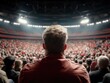 © Sergey - A large audience is seated in an amphitheater, viewed from behind a person in the foreground, under bright stage lights.