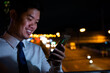 © sorapop - Modern businessman in neon-lit street using smartphone. Engaged in social media online shopping texting at night. Communication success in vibrant city.