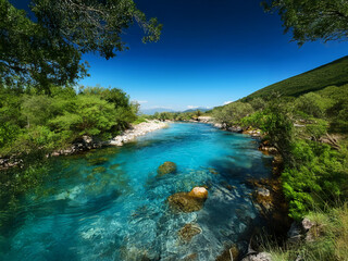 Poster - A vibrant turquoise river flows through a lush green valley under a brilliant blue sky.  Rocks and trees line its banks, creating a serene and picturesque landscape.