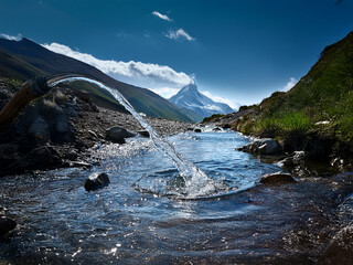 Poster - Crystal-clear water flows from a pipe into a pristine mountain stream.  The backdrop features majestic peaks and a vibrant blue sky.  A serene and untouched natural landscape.