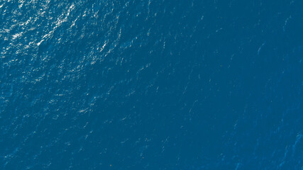 Poster - Flat lay top view of Ocean blue and calm with sun rays reflection on smooth waves as textured blue background for banner template or web page design. Water calm with smooth waves.