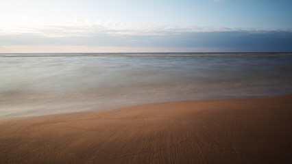 Poster - Beautiful Calm Sunset over Beach with Calm Ocean. Light Blue Water. Panoramic Seascape