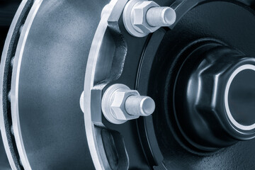 Poster - The wheel is black and silver with a white rim and is secured with large bolts and nuts like part of a large machine. The wheel is made of metal and has a black cap.
