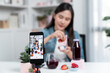 © Summit Art Creations - Selective focus smartphone with smiling young beautiful Asian reviewing mixed strawberry and cherry juice detox drink, presenting healthy product promotion selling on social media online. Stratagem.