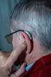 © L.Mendizabal - grandfather adjusting his hearing aid to listen