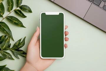 Fototapete - Female holding a blank mobile phone and using a laptop with a blank green screen