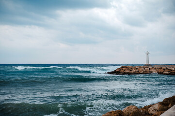 Wall Mural - Lighthouse on a Rocky Shore Under Cloudy Skies