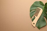 Wooden comb and monstera leaf on beige background, top view. Space for text