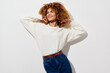 © SHOTPRIME STUDIO - Smiling woman with curly hair in a cozy white sweater, posing against a plain white background, exuding a joyful and carefree vibe Bright and stylish fashion concept