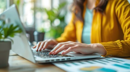 Wall Mural - A Woman in a Yellow Sweater Working Remotely on a Laptop from Home Office with Natural Light and Plants