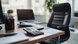 © Faxri - A contemporary white office with a black leather chair, a desktop computer, a calculator, and a wooden desk. The chief of staff has private office furnishings in the executive office.