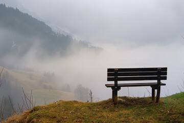 Poster - Serene view from a hillside bench overlooking fog-covered valleys and mountains during a misty morning