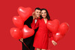 © Pixel-Shot - Loving young couple with heart-shaped balloons on red background. Celebration of Saint Valentine's Day