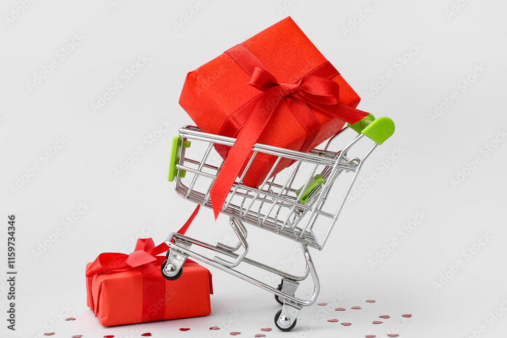 Small shopping cart with gift boxes on white background. Valentine's Day celebration