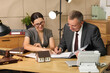 © Pixel-Shot - Lawyers with document holding meeting at table in office