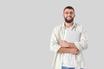 Young bearded man with laptop on light background