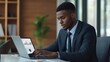 © ArpPSIqee - A young professional in a suit working on a laptop. In a modern office environment