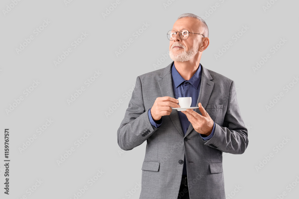 Senior businessman with cup of coffee on grey background