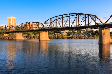 Wall Mural - A bridge spans a river with a city in the background