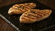 © bulegendut - Two grilled chicken breasts on slate.